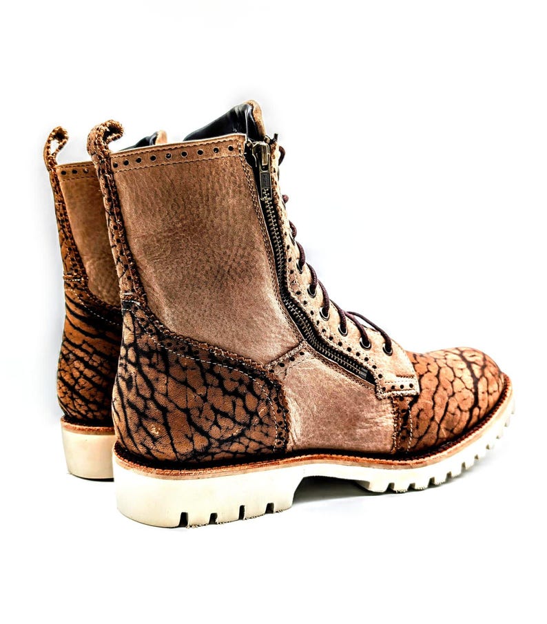 May include: Brown leather combat boots with a textured design and a side zipper. The boots have a white sole and brown laces. The heel is approximately 1.5 inches high.