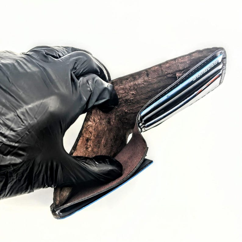 May include: A black leather wallet with a raw interior. The wallet is open and the inside is visible. The wallet is made of a soft, supple leather and has a simple design.