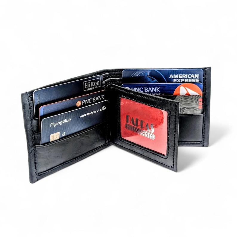 May include: Open black leather wallet with multiple card slots. The wallet contains credit cards from Hilton Honors, PNC Bank, Flyingblue, and American Express. A red card with "Dallas Restaurants" is visible.