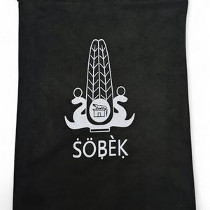 May include: Black drawstring bag with a white emblem and the word "S&Ouml;BEK". The emblem is a stylized design with a central element and flanking curved shapes. The bag is made of a soft, opaque material.