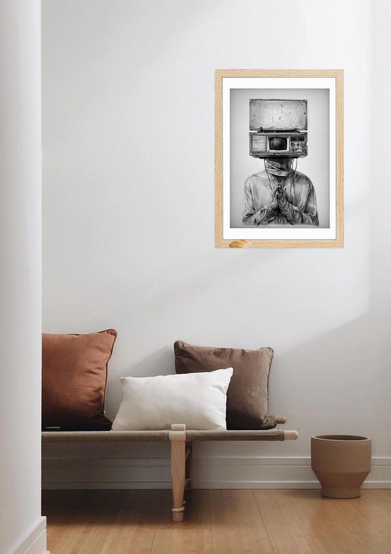 May include: Black and white framed art print. The artwork depicts a person with a vintage radio head. The person is wearing a long-sleeved shirt and has their hands clasped in front of them. The art is displayed on a white wall.