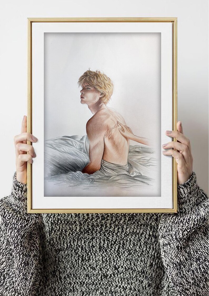 K&ouml;nnte beinhalten: Ein gerahmter Kunstdruck mit einer Bleistiftzeichnung einer Person mit blonden Haaren, die auf einem Bett sitzt. Das Kunstwerk befindet sich in einem goldenen Rahmen. Der R&uuml;cken der Person ist sichtbar, mit einem Tattoo. Das Kunstwerk wird von einer Person gehalten, die einen schwarz-wei&szlig;en Pullover tr&auml;gt.