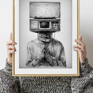 May include: Black and white art print of a person with a vintage television and radio in place of a head. The person is wearing a button-down shirt and has their hands clasped in front of them. The artwork is framed in a gold frame.