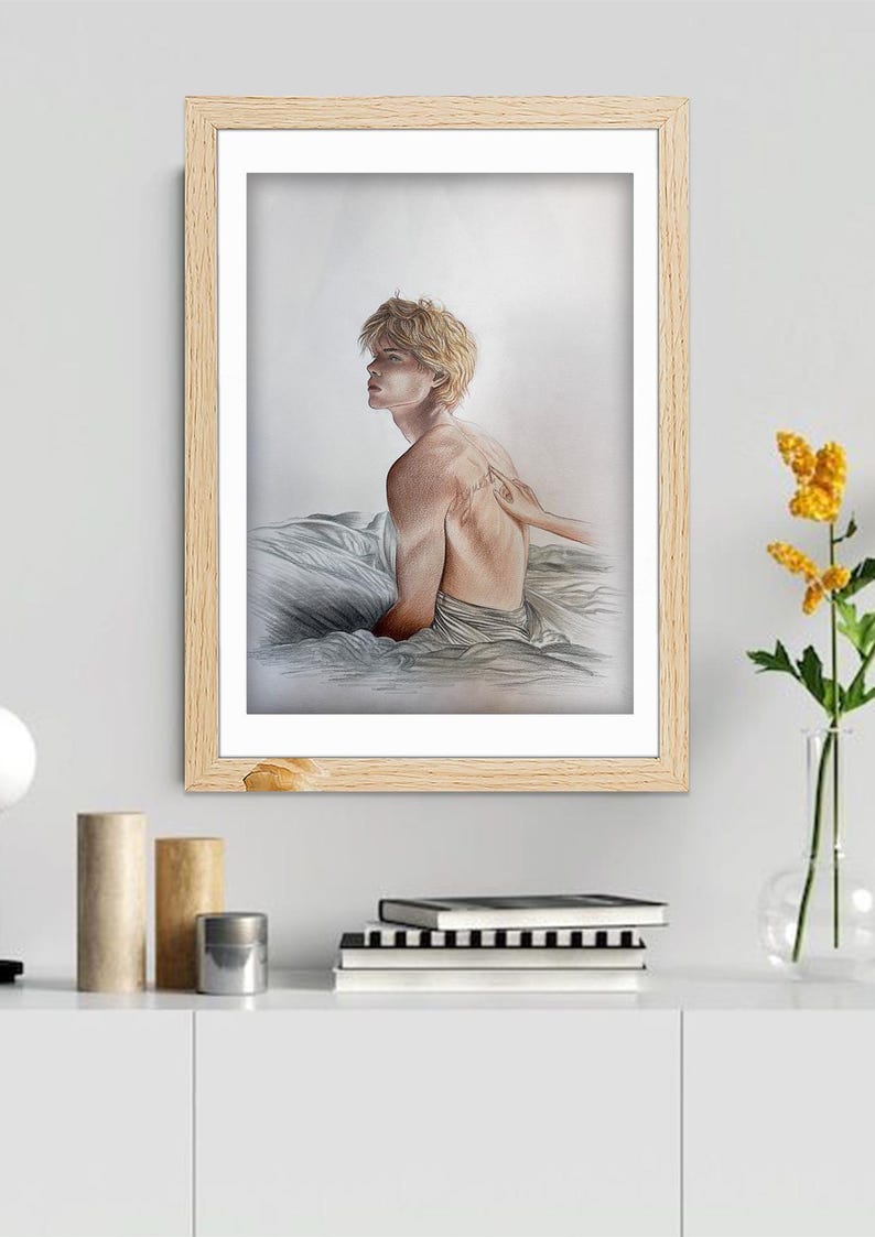 K&ouml;nnte beinhalten: Ein gerahmtes Kunstwerk mit einem Aquarellportr&auml;t einer Person mit blonden Haaren, die sitzt und zur Seite blickt. Das Kunstwerk befindet sich in einem hellen Holzrahmen und wird auf einem wei&szlig;en Schrank ausgestellt. Eine Hand ber&uuml;hrt den R&uuml;cken der Person. Rechts ist eine Vase mit gelben Blumen.
