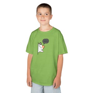 Peut inclure: T-shirt vert citron avec un chat de dessin animé. Le chat, avec une fourrure blanche et des détails noirs et orange, apparaît derrière une ligne noire. Une bulle de dialogue au-dessus du chat dit "Chat-Ju".