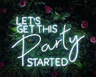 May include: White neon sign with the text "Let's get this party started" against a backdrop of green foliage and pink flowers.