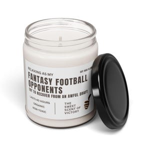 May include: A clear glass jar candle with a black lid. The candle has a white label with black text that reads "Relaxing as my Fantasy Football Opponents try to recover from an awful draft." The candle is organic and non-toxic.