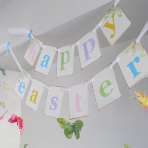 May include: A white banner with the words "happy easter" in pastel colors. The banner is decorated with butterflies and is hanging from the ceiling.