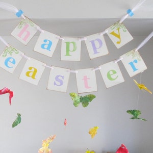 May include: A white banner with the words "Happy Easter" in colorful letters. The banner is strung with white ribbon and decorated with small butterflies.