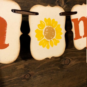 May include: A fall-themed banner with the word "home" in orange letters, a sunflower, and a brown ribbon.