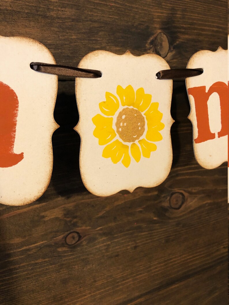 May include: A fall-themed banner with the word "home" in orange letters, a sunflower, and a brown ribbon.