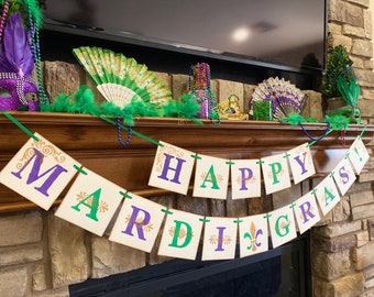 May include: A banner with the words "Happy Mardi Gras!" in purple, green, and gold letters. The banner is strung across a wooden mantelpiece with green and purple beads and a green feather fan.