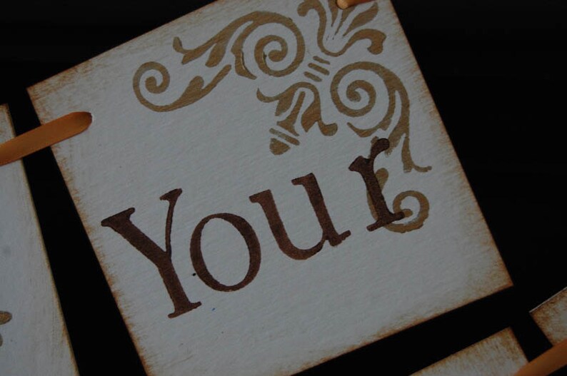 May include: A white sign with brown lettering and a decorative design in the top corner. The sign says "Your".