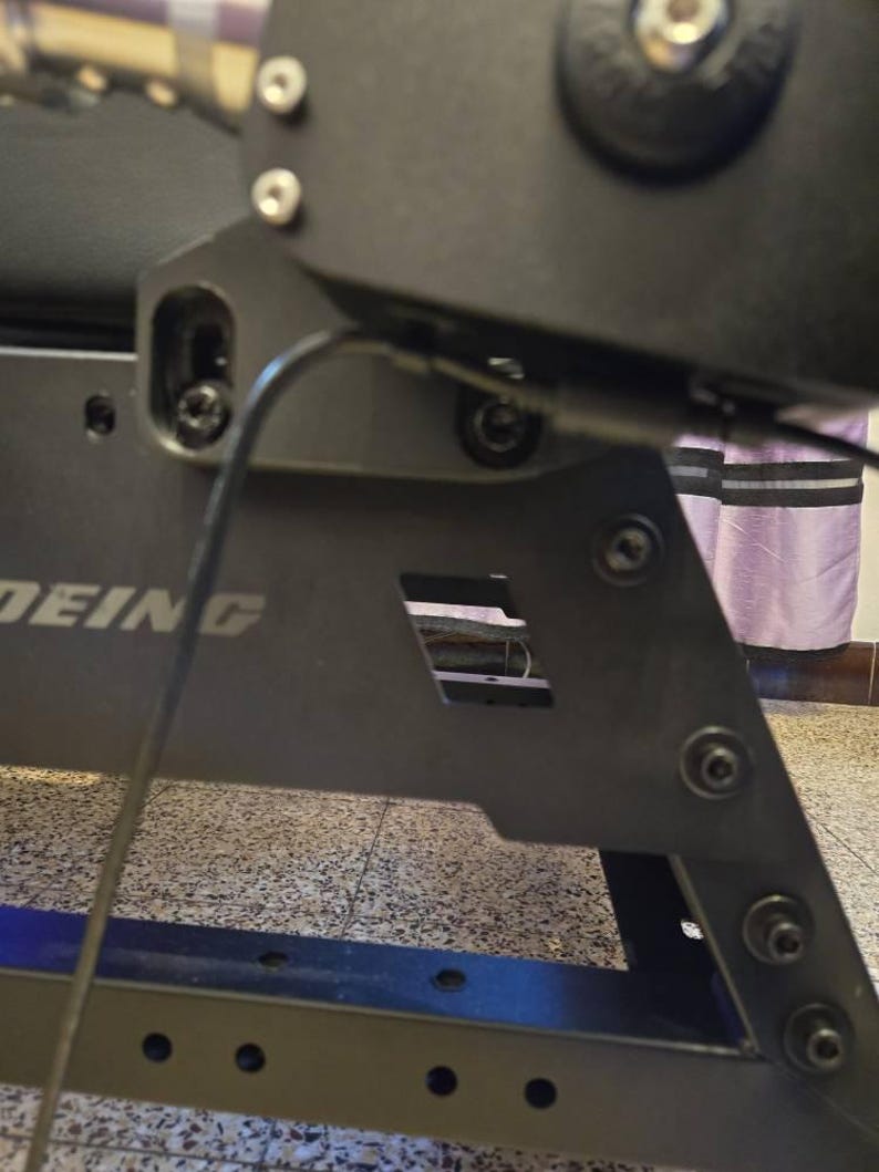 May include: Close-up of a black metal frame with the word "DEING" printed on it. The frame has several screws and a black wire running through it.