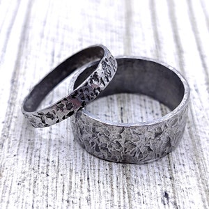 May include: Two silver rings with a hammered texture. The rings are stacked on top of each other.