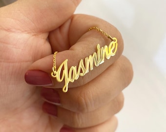 May include: A gold necklace with the name "Jasmine" spelled out in cursive script.