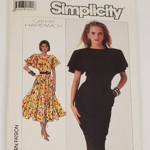 Può includere: Modello di cucito Simplicity con due modelli di abiti. Un abito è un abito nero midi con maniche corte. L'altro abito è un abito midi con un motivo floreale giallo, arancione e verde.