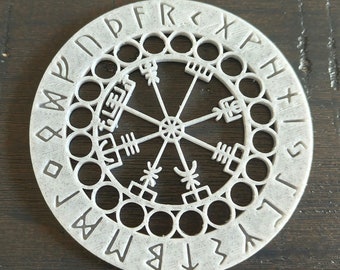 May include: White circular compass with a Vegvisir symbol in the center. The compass is surrounded by a ring of runes, including "N", "P", "F", "R", "K", "X", "P", "H", "I", "S", "L", "I", "T", "B", "M", "W", "O", "D", "M", "Y".