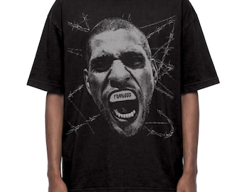 May include: A black short-sleeve t-shirt featuring a large, high-contrast graphic of a person's face with an open mouth. The word "FEARLESS" is printed on a white rectangular bar across the mouth, surrounded by a barbed wire design.
