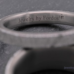 May include: Two silver rings with a textured finish. The top ring has the inscription "Jewelry by Fordos" on the inside.
