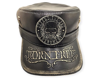 May include: Black leather military-style cap with a distressed brim. The cap features a circular emblem with a skull and the text "DEFEND THE 2ND AMENDMENT." The brim displays the words "BORN FREE" in a decorative font.
