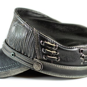 May include: A black leather cap with a distressed look. The cap has a winged design on the side and a button closure on the front.