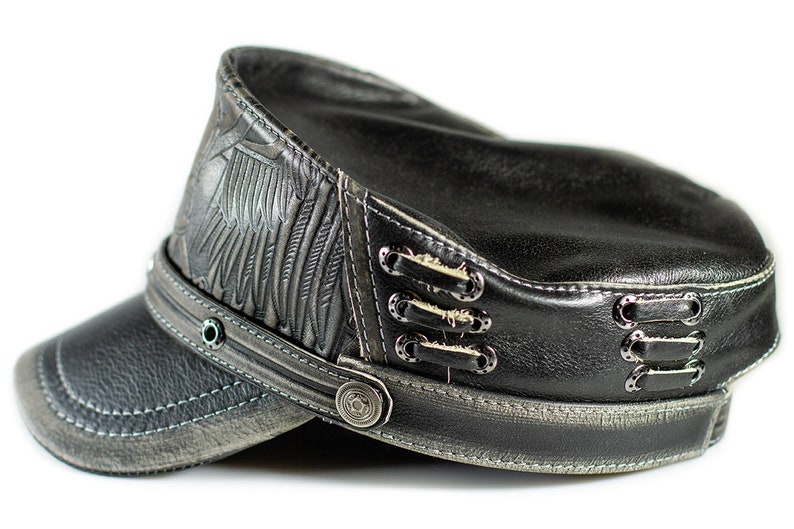 May include: A black leather cap with a distressed look. The cap has a winged design on the side and a button closure on the front.