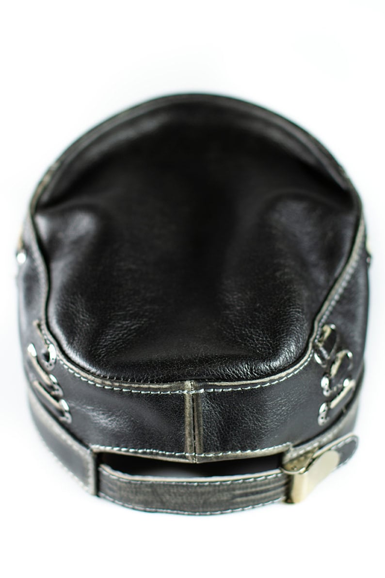 May include: A black leather baseball cap with a silver buckle and stitching around the brim.