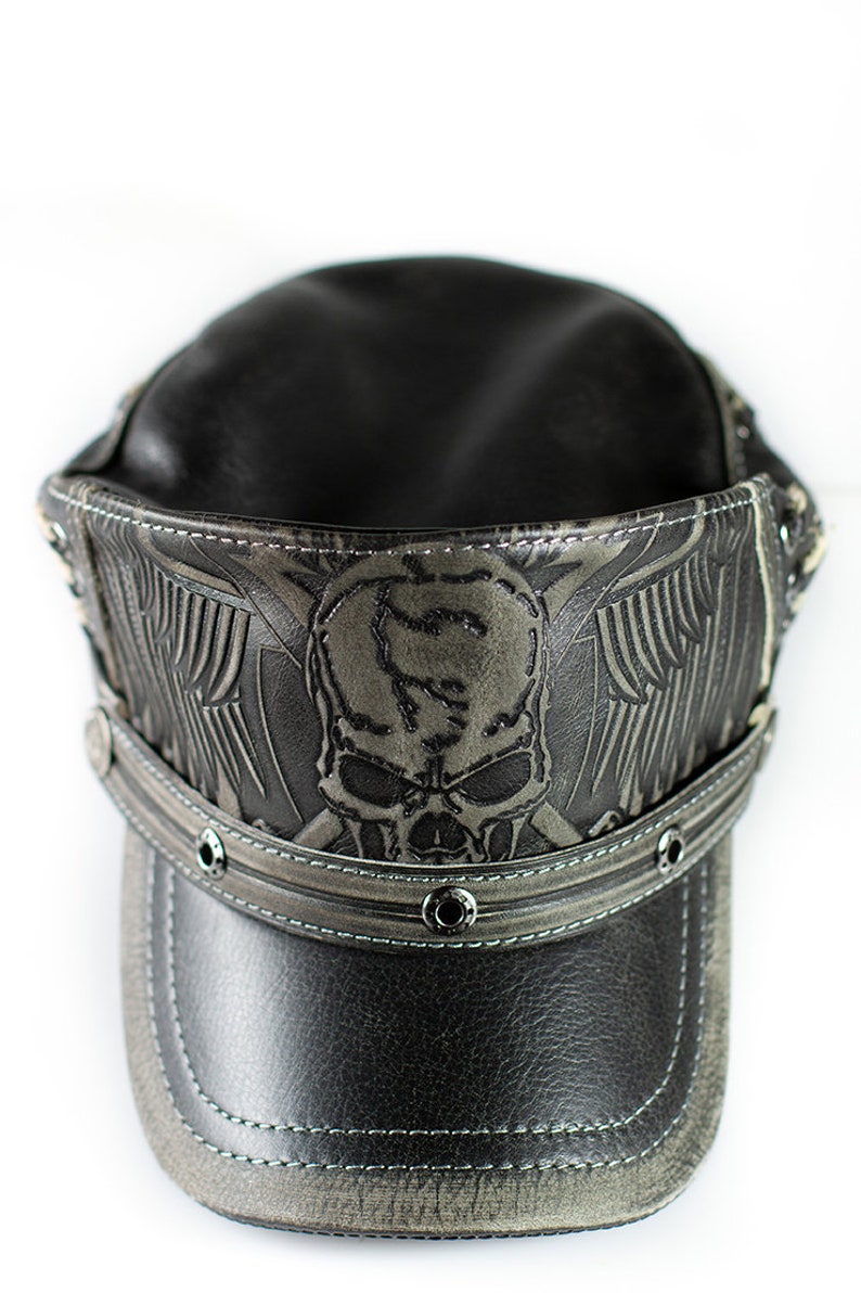 May include: A black leather cap with a skull and wings design. The cap has a stitched brim and metal rivets.