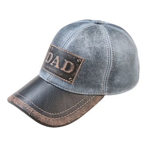 May include: A blue and black leather baseball cap with a brown leather patch that says "DAD" on it.