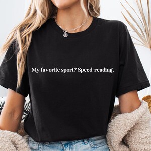 May include: A black t-shirt with the text "My favorite sport? Speed-reading." printed in white.