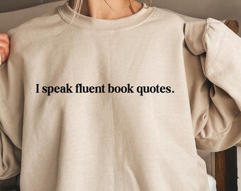 May include: A beige sweatshirt with the text "I speak fluent book quotes." printed on the front.