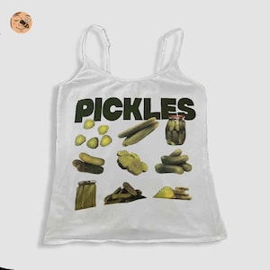 May include: White vest top with the word "PICKLES" in dark green. The design includes various pickle images: whole, sliced, and in a jar. A fun, food-themed garment.