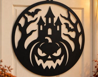May include: A circular black wall hanging featuring a laser-cut design of a haunted castle, a large jack-o'-lantern with a jagged face, bare tree branches, and two flying bats. The piece is suspended from a small metal hook on a door.