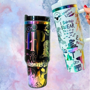 Puede incluir: Dos tazas de viaje de acero inoxidable con temática de Harry Potter. Una taza es negra con un acabado iridiscente arcoíris y presenta el escudo de Hogwarts, las palabras "Always" y otros símbolos de Harry Potter. La otra taza es blanca con un acabado iridiscente arcoíris y presenta las palabras "Juro solemnemente que no tengo nada bueno que hacer" y otros símbolos de Harry Potter.