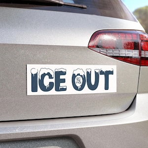 May include: A white rectangular bumper sticker with the words "ICE OUT" in dark blue, with the letters appearing to be covered in snow. The words "GET THE F*CK" are in a smaller font within the letter "O".