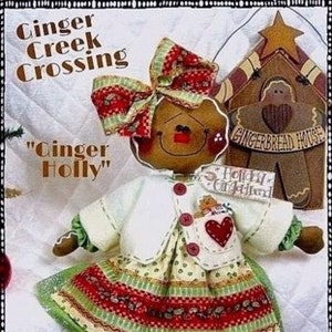 May include: Gingerbread doll with a red and green dress, a white sweater, and a red bow. The doll is holding a small gingerbread house with the text "Gingerbread House" on it. The doll is standing on a white background with the text "Ginger Creek Crossing" and "Ginger Holly" above it. The text "2012" is in the bottom right corner of the image.