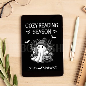 May include: A black and white illustration of a ghost wearing a beanie hat and holding a pumpkin and a cup of coffee. The text "Cozy Reading Season" is above the ghost and the text "Stay Spooky" is below the ghost.