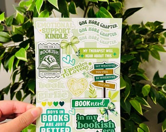Op de afbeelding: Een vel stickers met een groen-wit geruite achtergrond. De stickers bevatten verschillende boek-gerelateerde zinnen, waaronder "Emotional Support Kindle", "Bookish", "Enemies to Lovers", "Book Girl", "Boys in Books Are Just Better", "Book Nerd" en "In My Bookish Era".