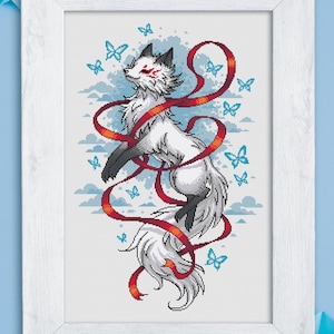 May include: Framed artwork featuring a white fox with red accents and a flowing red ribbon. The fox is surrounded by blue butterflies and clouds. The artwork is in a white frame.