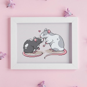 Puede incluir: Un bordado de punto de cruz enmarcado en blanco con dos ratones grises y blancos besándose con corazones rosas en el fondo.