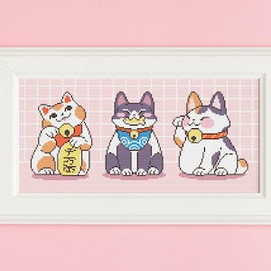 Peut inclure: Trois figurines de chat porte-bonheur japonais, Maneki-Neko, en dessin animé, dans un cadre blanc. Les chats sont blancs, noir et blanc, et orange et blanc. Ils tiennent tous une pièce d'or et ont une clochette autour du cou. L'arrière-plan est une grille rose.