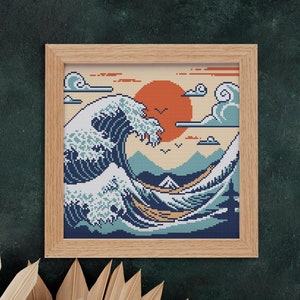 May include: A framed cross-stitch artwork depicting a blue and white wave crashing against a yellow and orange sunset. The wave is stylized in a pixelated design, reminiscent of a video game.