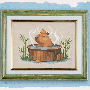 May include: A cross-stitch embroidery of a capybara wearing an orange slice on its head, relaxing in a wooden tub filled with water and surrounded by bamboo.