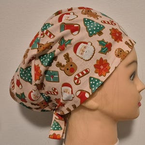 May include: A pink scrub hat with a Christmas-themed print featuring Santa Claus, reindeer, candy canes, and Christmas trees.