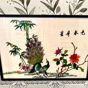 May include: A framed embroidery depicting a pair of peacocks with green and blue feathers, bamboo stalks, and red and pink flowers. The Chinese characters "春 娇 春色" are embroidered in the top right corner.