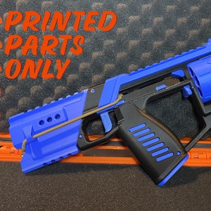May include: A blue and black 3D printed toy gun with a printed text "PRINTED PARTS ONLY" on the top. The gun is in a black and orange case.