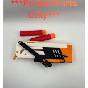 May include: A white, black, and orange toy gun with two red and orange projectiles. The toy gun has a black handle and the text "***Printed Parts Only***" in orange.