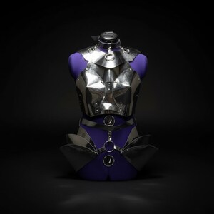 May include: A silver-colored metal chest and waist armor set displayed on a purple dress form. The armor features a series of geometric plates and circular accents. The background is black.