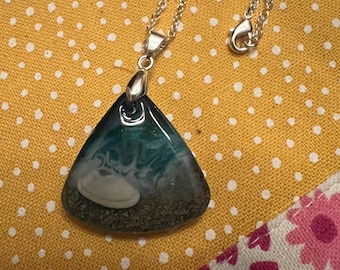 May include: A silver chain necklace with a triangular pendant featuring a green, blue, and white marbled design with glitter accents.